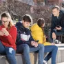 Adolescents assis sur un muret, deux d'entre eux discutent et deux autres sont sur leur téléphone portable